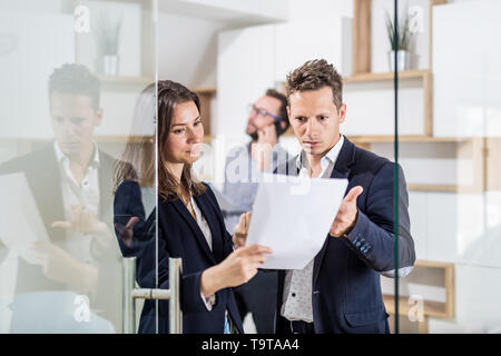 Manager argumentieren mit seinen weiblichen Angestellten neben dem Büro Tür. Stockfoto