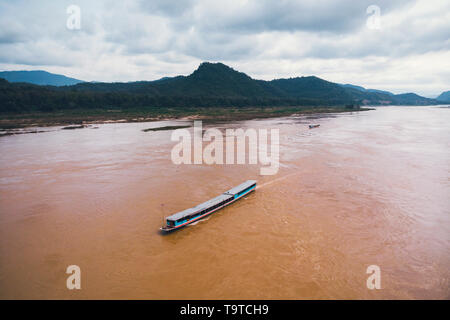 Blick von oben. Beeindruckende Luftaufnahme eines traditionellen Long tail Boot auf dem Mekong Fluss, Luang Prabang, Laos. top Aussicht, Luftaufnahme Stockfoto