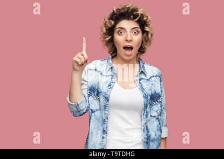 Idee. Portrait von überrascht junge Frau mit Curly Frisur im lässigen Stil stehen und an der Kamera mit entsetzten Gesicht und Idee finger Geste. Stockfoto