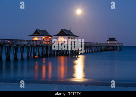 Einstellung Vollmond und am frühen Morgen in der Dämmerung über den Naples Pier, Naples, Florida, USA Stockfoto