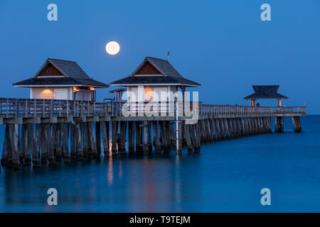 Einstellung Vollmond und am frühen Morgen in der Dämmerung über den Naples Pier, Naples, Florida, USA Stockfoto