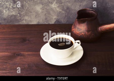 Kaffee in weiße Tasse und Lehm cezve auf Holz- Hintergrund. Getönt Stockfoto