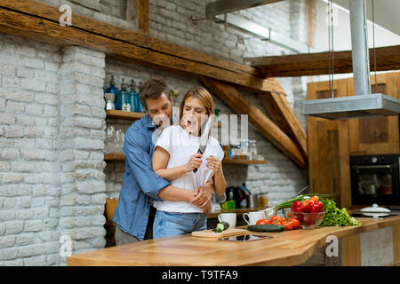 Schöne fröhliche junge Paar Abendessen kochen zusammen und Spaß an der rustikalen Küche Stockfoto