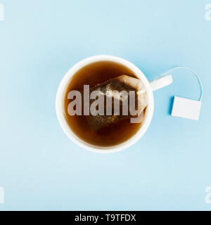 Tasse Kaffee und Teebeutel auf blauem Hintergrund. Ansicht von oben. Essen Hintergrund Stockfoto