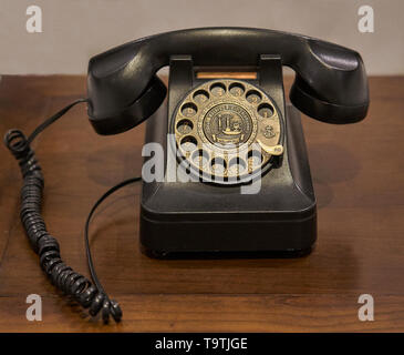 Ein vintage Dunkelbraun Drehschalter Telefon auf einem alten Holztisch gelegt. Stockfoto