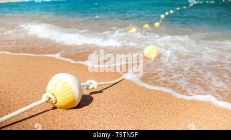 Closeup Bild aus Kunststoff Bojen im Einklang mit Seil liegen auf dem Meer Strand verbunden. Perfekte Aufnahme Sommerurlaub Urlaub am Meer zu illustrieren. Stockfoto