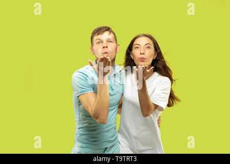 Die schöne junge Paar Brustbild auf Green Studio Hintergrund isoliert. Mann und Frau stehen und senden Küsse. Mimik, menschliche Emotionen Konzept. Trendige Farben. Stockfoto