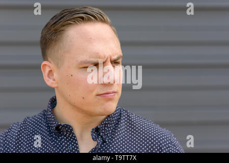 Nahaufnahme eines Nachdenklichen jungen Mann beiseite, mit einem zweifelhaften Ausdruck betont Stockfoto