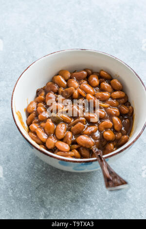 Hausgemachten Grill gebackene Bohnen in Porzellan Schüssel. Ökologische Lebensmittel. Stockfoto