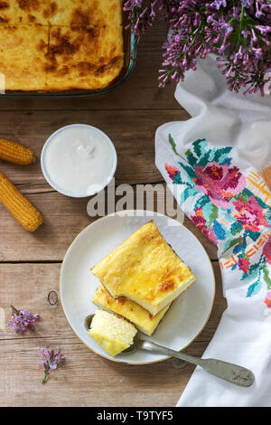 Traditionelle rumänische oder Moldawischen Cottage Käse Auflauf mit Maismehl, serviert mit Honig und Sauerrahm. Rustikaler Stil, selektiven Fokus. Stockfoto