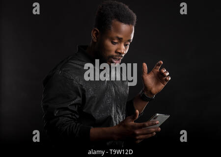 Portrait von schockiert und attraktive african american man betäubt, verwirrt und überrascht, während das Lesen von Nachrichten im Internet, empfangen mich unglaublich Stockfoto