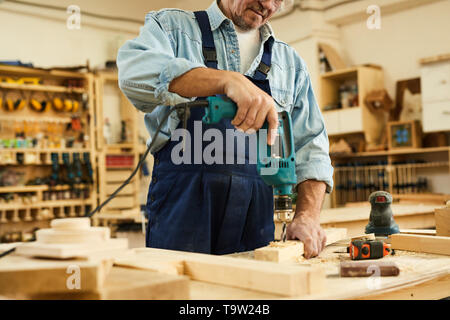 Den mittleren Abschnitt Portrait von Reifen Tischler bohren Holz während in der Tischlerei arbeiten, kopieren Raum Stockfoto