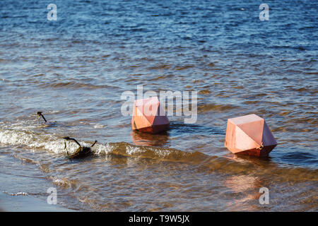 Sicherheit auf dem Wasser. Zwei große orange Bojen und eine Lüge horizontal Anker am Ufer auf dem Wasser des Flusses Bay Stockfoto