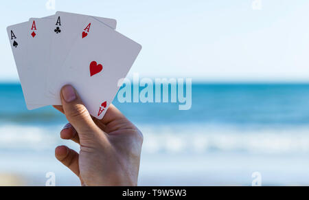 Spiel im Freien am Strand, vier in die Hand des Spielers mit Meer und Himmel Hintergrund Asse Stockfoto