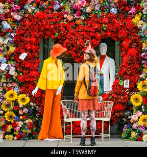 Belgravia, London, UK, 20. Mai 2019. Eine junge Frau, die in einem farbenfrohen Outfit nimmt Schnappschüsse von den ebenso farbenfrohen Display. Das Hotel Hari hat eine spektakuläre Herzförmige floral Display mit 60er Jahre inspirierten Figuren und eine Liebe Sitz, das populär ist mit Passanten unter Foto erstellt. Credit: Imageplotter/Alamy leben Nachrichten Stockfoto