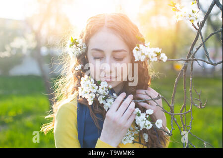 Glückliche junge Frau genießen Sie den Geruch der Blumen über Frühling Garten Hintergrund Stockfoto