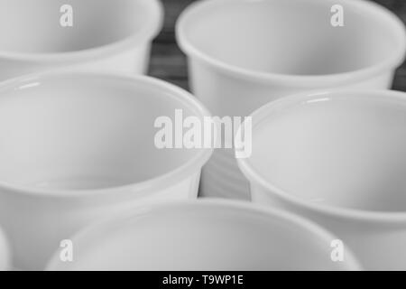 Eine Gruppe von Weißen Plastikbecher auf einem Schwarzen Tisch montiert. Makro Nahaufnahme Stockfoto