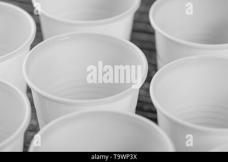 Eine Gruppe von Weißen Plastikbecher auf einem Schwarzen Tisch montiert. Makro Nahaufnahme Stockfoto