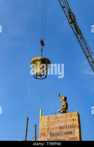 GARDA, Gardasee, Italien - September 2018: Turmdrehkran, die ein Arbeitnehmer zu senken einer starken Stahl eimer Beton auf einer Baustelle in der Regie Stockfoto