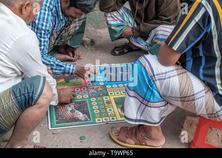 Vier Männer sind gesehen, da sie ludo König spielen, sitzen auf der Straße in Dhaka, Bangladesh. Stockfoto