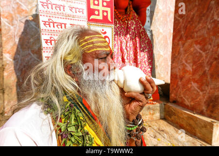 Indischen Sadhu Baba im Hochformat spielen Muschelschale vor Hanuman Tempel in Varanasi Indien. Stockfoto