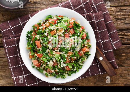 Frische vegane Tabbouleh Salat aus Tomaten, Petersilie, Zwiebel und Couscous auf Platte, fotografiert Overhead Stockfoto