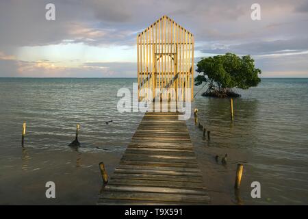 Sonnenuntergang Himmel Panoramablick auf die Landschaft von isolierten hölzerne Tor über die Fischerei Dock Pier mit fernen Karibischen Meer am Horizont auf Caye Caulker Insel, Belize Stockfoto