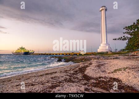 Dramatischer Sonnenuntergang Himmel Farben über einen karibischen Strand und Car Ferry Pier Leuchtturm in Cozumel, Mexiko Halbinsel Yucatan Stockfoto