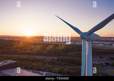 Schönen Sonnenuntergang hinter Wind Turbine gefunden in Sheffield, East Yorkshire, Großbritannien vor Bäumen und Gebäuden - Frühling 2019 Stockfoto