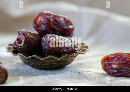 Getrocknete Datteln Obst in einer Schüssel auf Leinen, hautnah. Stockfoto