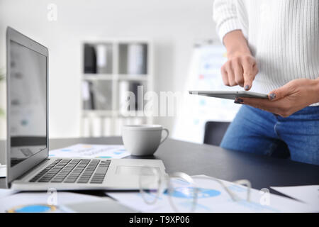 Junge Frau mit modernen Geräten arbeiten im Büro Stockfoto