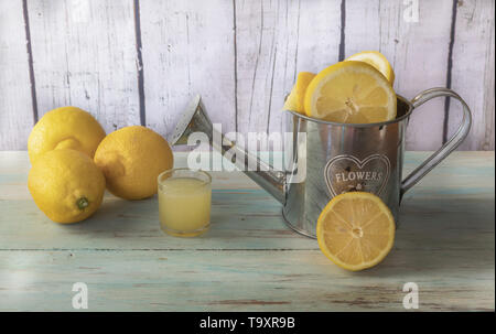 Noch immer leben von Zitronen auf ein Metall Gießkanne Zitronensaft und. Licht Holz Hintergrund Stockfoto