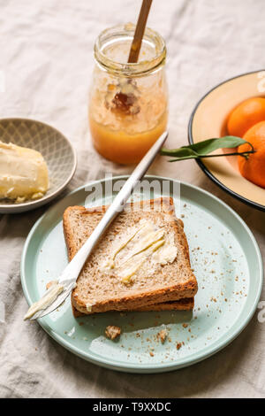 Brot mit Butter und lecker Tangerine jam auf Tisch Stockfoto