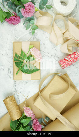 Null - Abfall Geschenkverpackung flatlay Overhead mit Kraftpapier, Jute und Baumwolle Bänder und Garten Blumen für umweltfreundlichen Lebensstil. Stockfoto