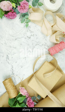 Null - Abfall Geschenkverpackung flatlay Overhead mit Kraftpapier, Jute und Baumwolle Bänder und Garten Blumen für umweltfreundlichen Lebensstil. Stockfoto