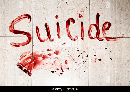 Wort Selbstmord im Blut auf dem Boden geschrieben Stockfoto
