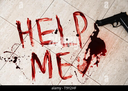 Text HELFEN MIR in Blut und Gewehr auf den Boden geschrieben Stockfoto