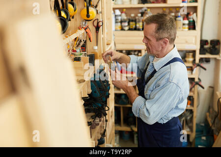 Seitenansicht Portrait von älteren Tischler Auswahl Schrauben in Werkstatt, Platz kopieren Stockfoto