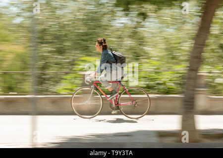 Cordoba, Spanien - 10. Mai 2019: Frau Radfahrer mit gestreiften Hosen Reiten durch die Straße. Stockfoto