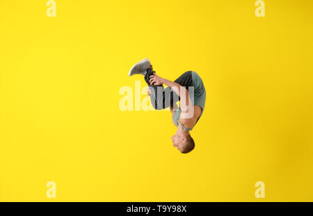 Junge männliche Tänzer tun Flip auf farbigen Hintergrund Stockfoto