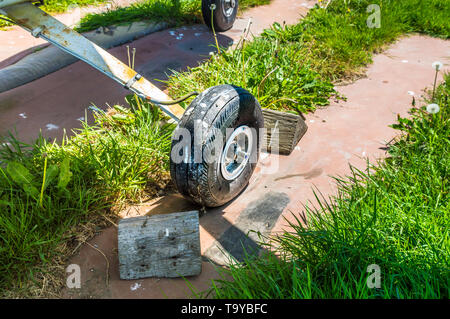 Alten kleinen einmotorigen Flugzeug Rad und Holzkeile auf Parkplatz pad, splattered mit Schmutz und Vogel Ausscheidungen. Stockfoto