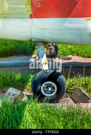 Alten kleinen einmotorigen Flugzeug Räder und Holzkeile auf Parkplatz pad, splattered mit Schmutz und Vogel Ausscheidungen. Stockfoto