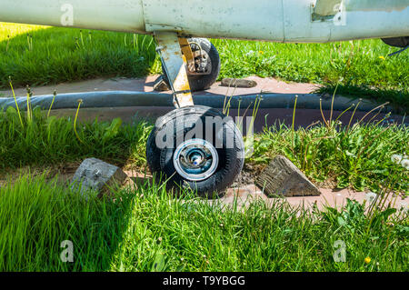 Alten kleinen einmotorigen Flugzeug Rad und Holzkeile auf Parkplatz pad, splattered mit Schmutz und Vogel Ausscheidungen. Stockfoto