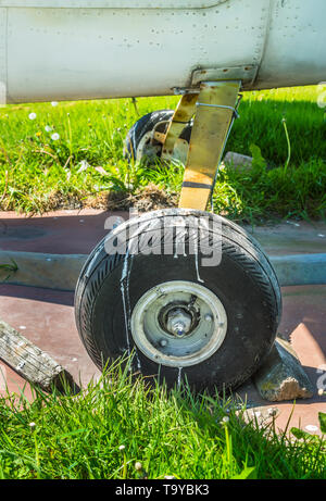 Alten kleinen einmotorigen Flugzeug Rad und Holzkeile auf Parkplatz pad, splattered mit Schmutz und Vogel Ausscheidungen. Stockfoto