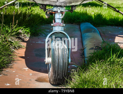 Alten kleinen einmotorigen Flugzeug Fahrwerk auf begrünten Parkplatz Pad an einem sonnigen Tag. Stockfoto