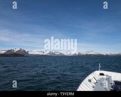 Ein Blick auf die schneebedeckten Berge, auf einem der South Georgia Islands und den Bogen und Deck eines Kreuzfahrtschiffes von oben. Stockfoto