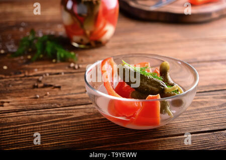 Schüssel mit leckerem vergorene Gurken und Paprika auf hölzernen Tisch Stockfoto