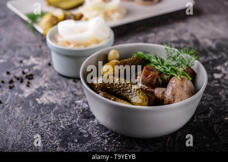 Schüssel mit leckerem vergorene Gurken auf grunge Tabelle Stockfoto