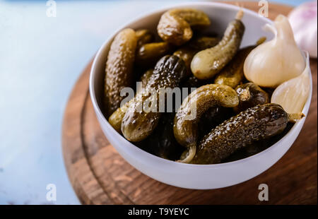 Schüssel mit leckerem vergorene Gurken und Knoblauch auf Tisch Stockfoto