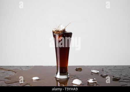 Glas Spritzer Cola auf dem Tisch gegen den hellen Hintergrund Stockfoto